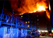 Brændende bygning med kraftig tagbrand og stillads i forgrunden